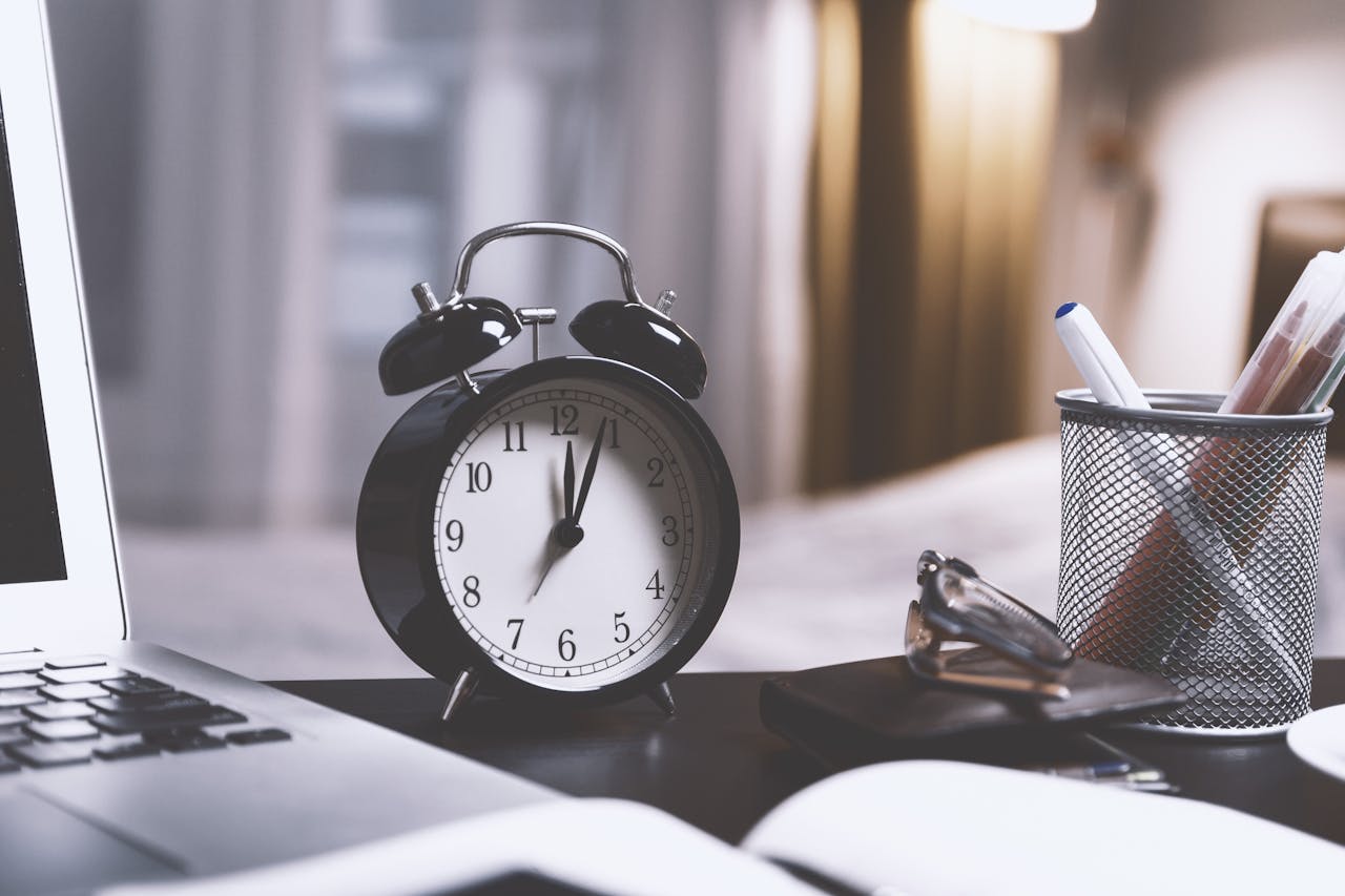 Clock with a notebook on a table symbolizing the concept of time management