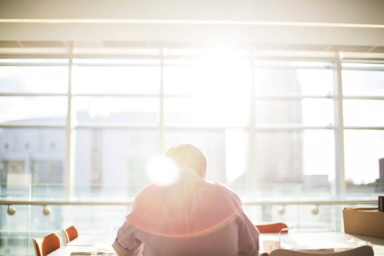 A person sitting in front of the table and working under the sunlight in the morning