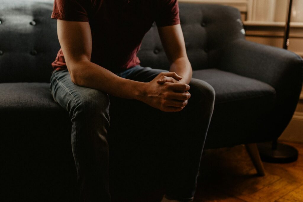 A man sitting on a coach thinking which decision is better to make